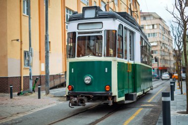 İstanbul 'daki Kadıköy-Moda hattında, kentsel binalar ve elektrik direkleriyle çevrili beyaz bukleli eski yeşil bir tramvay seyahat ediyor. Bir şehir ortamında toplu taşıma nostaljik bir mod.