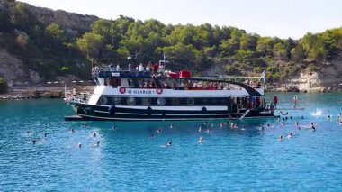 FALIRAKI, GREECE: 26 Ağustos 2024: Gezici turistler Yunanistan 'ın Rhodes Adası' ndaki Anthony Quinn körfezinde kristal berrak denizde yüzmeye hazırlanıyorlar. İnsanlar yazın denizde iyi vakit geçiriyorlar..