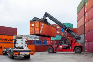 İstanbul, Beylikduzu - Türkiye - Lojistik İthalat Şirketi için 07.07.2023 konteyner sahası, renkli konteyner yığını. Yükleme anından görüntü. Vinç bir konteynır ve kamyon yükleme için bekliyor..