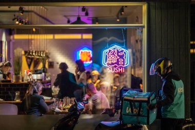 Kopenhag, Danimarka Wolt Motosikleti ve Vesterbrogade 'deki bir suşi restoranının önünde yemek getiren adam..