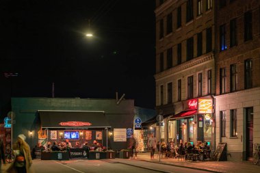 Copenhagen, Denmark People sitting outdoors at night at a bar. clipart