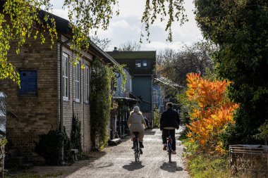 Copenhagen, Denmark, A young couple ride bikes through Christiania, clipart