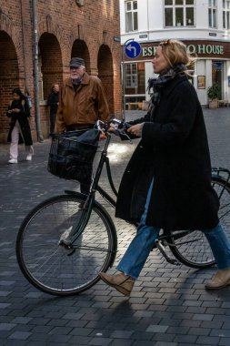 Kopenhag, Danimarka tarzı bir kadın şehir merkezinde bir meydanda bisikletiyle yürüyor..