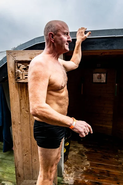 Copenhagen, Denmark A man stabds at a sauna door in  the traditional Danish sauna gus ritual of a sauna and a dip in the sea.