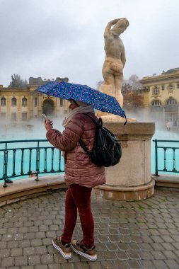 Budapeşte, Macaristan Şemsiyesi ve telefonu olan bir kadın Szechenyi Spa 'da.