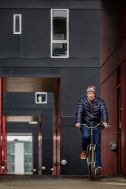 Kopenhag, Danimarka Güney Liman Bölgesi 'nde bir adam modern bir konut kompleksinde bisiklet sürüyor.