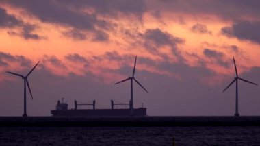 Kopenhag, Danimarka Rüzgar türbinleri şafak vakti Öresund Boğazı üzerinde bir gemi geçerken dönüyor.  