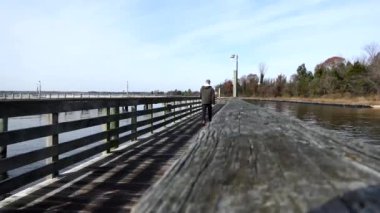 Solomons, Maryland USA Patuxent nehrinin kıyısındaki gün ışığında bir adam ahşap bir rıhtımda yürüyor.. 