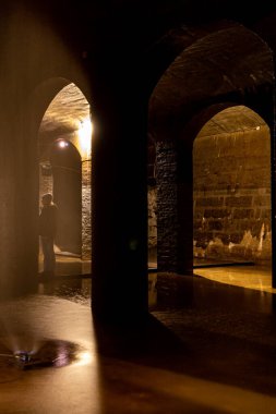 Kopenhag, Danimarka Frederiksberg bölgesindeki eski sarnıçta yeraltı kemerlerinin yanında bir kadın duruyor..