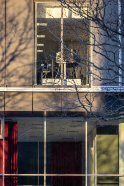 Kopenhag, Danimarka, Orestad bölgesindeki bir binanın penceresinde çalışan bir ofis çalışanı..