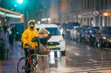 Kopenhag, Danimarka. Şehir merkezindeki Istegade 'de yağmur altında bir bisikletçi..