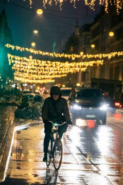 Kopenhag, Danimarka. Şehir merkezindeki Istegade 'de yağmur altında bir bisikletçi..