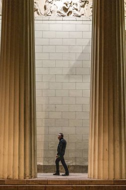 Kopenhag, Danimarka 'da Kopenhag Katedrali' nin basamaklarında bir adam yürüyor, ya da Vor Frue Kirke, gece vakti..