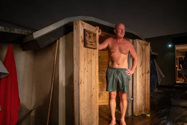 Copenhagen, Denmark A man stands outside a door leading to a warm sauna.