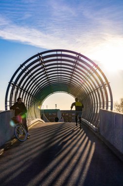 Copenhagen, Denmark A bicyclist and a jogger on a covered bridge over the railway track in the Amager district.
