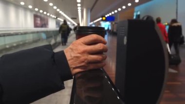Kopenhag, Danimarka. Terminaldeki hareketli kaldırımda bir kişi hazır kahve tutuyor.. 