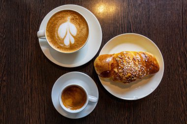 Malmo, Sweden Two coffees on a cafe table with a sweet bun and hands.