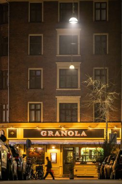 Copenhagen, Denmark  A pedestrian walks by the  landmark Granola restaurant at night on Varnedamsvej.
