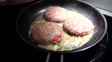 Hamburgers frying in a pan