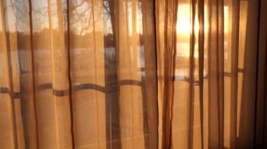 Solomons Island, Maryland, USA The sun rises through a window behind curtains. 