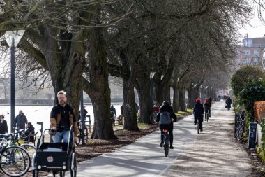 Copenhagen, Denmark  A man rides a cargo bike in the downtown along a lake.