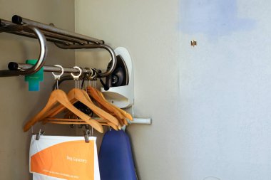 An iron, ironing board and laundry bag hanging inside a motel room.