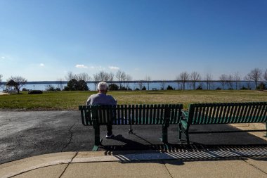 Solomons, Maryland USA Son sınıf öğrencisi gündüzleri Patuxent nehrine bakan bir bankta oturuyor..