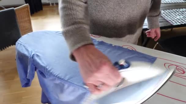 Mężczyzna Wyprasuje Niebieską Koszulę Desce Prasowania — Wideo stockowe