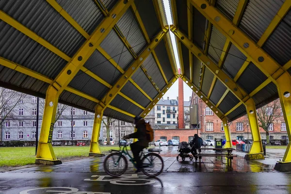 Kopenhag, Danimarka 'da Norrebro bölgesindeki açık bir yolun altında motosikletler geçerken bir adam oturuyor..