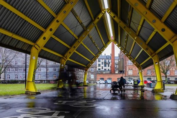 デンマークのコペンハーゲン自転車が転がるとき 男は雨の中ノルレブロ地区の大きなオープンルードの下に座っています — ストック写真