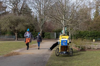 Kopenhag, Danimarka Bir adamın bacakları Norrebro 'daki bir parkta park halindeki bir banktan ve park halindeki bir kargo bisikletinden dışarı fırladı.