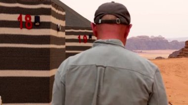 Wadi Rum, Jordan, bir adam çöl kampına gitmek için tahta yolda çantasıyla yürüyor..