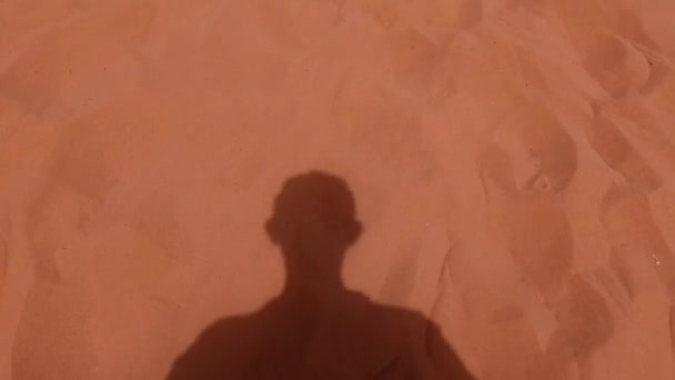 ヨルダンのワディ ラム砂漠の赤い砂丘を歩いている男の影 — ストック動画