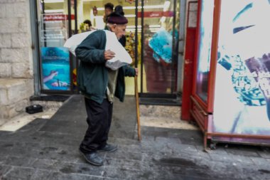 Amman, Jordan Amman şehir merkezinde Kral Faysal Meydanı 'nda yaşlı bir adam, yoğun bir yolda, omuzlarında ağır çantalar taşır..