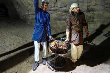 Wadi Rum, Jordan Bedevi erkekleri çöldeki bir kamp alanında uzun zamandır kumda konuklara pilav ve kuzu eti sunuyorlar..