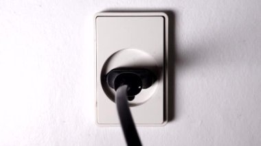 Bir el, elektrik kontağını prize takar.. 