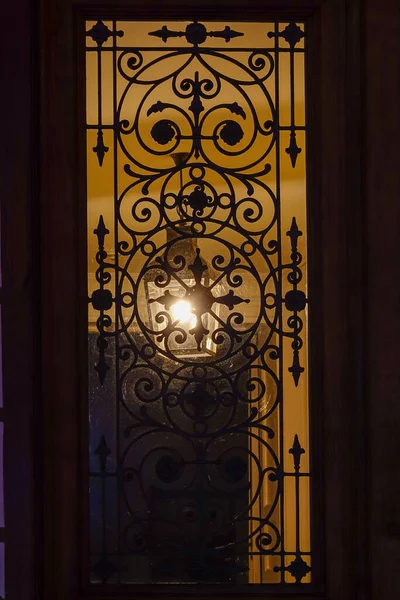 丹麦哥本哈根一个古老的门窗 晚上有一个锻铁烤架 走廊里有一盏灯 — 图库照片