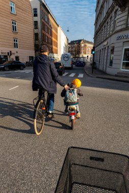 Kopenhag, Danimarka. Bir baba, genç oğluna Vesterbrogade 'de yoğun bir kavşakta bisiklet sürmesi için rehberlik eder..