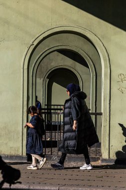 Kopenhag, Danimarkalı yayalar gün batımında Norrebro bölgesinde tarihi kemerler arasında yürürler..