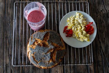 Taze pişmiş haşhaşlı ekmek, çırpılmış yumurta ve smoothie..