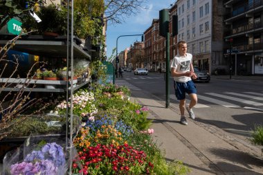 Kopenhag, Danimarka Erkek bir koşucu güneşli bir günde Gammel Kongevej 'de bir çiçekçinin önünden geçiyor.