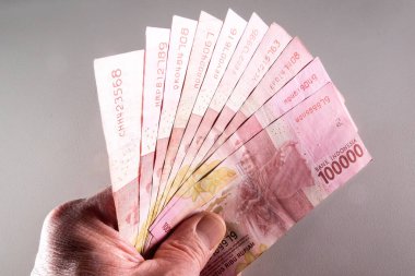 Bir el, Endonezya 'dan 100.000 Rupiah' lık banknot koleksiyonu tutar..