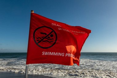 Canggu, Bali, Endonezya Sahilde kırmızı bir bayrak yüzmenin yasak olduğunu söylüyor.