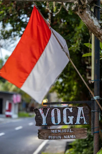 印度尼西亚巴厘 一面印度尼西亚国旗和一个瑜伽标志在街道旁边 — 图库照片