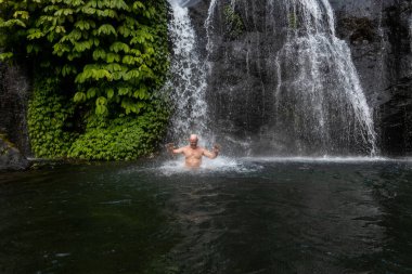 Banyumala Şelalesi, Bali, Endonezya Bir adam şelalede banyo yapar.