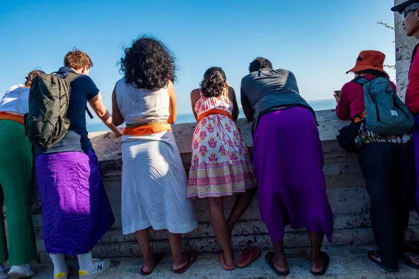 stock image Uluwatu, Bali, Indonesia Tourists wearing obligatory sarongs visiting the Uluwatu Temple and looking over the edge to the sea.