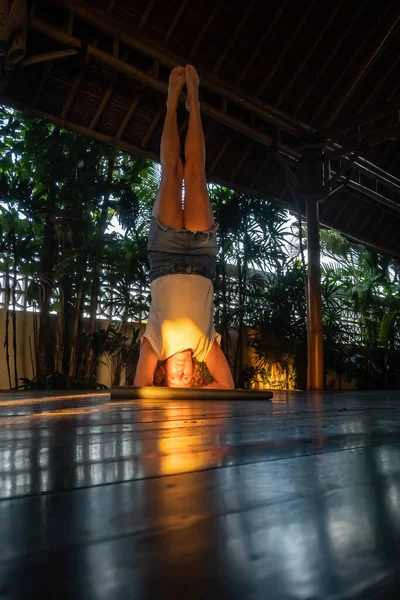 印尼巴厘 乌布德一个女人在夕阳西下的瑜伽集会上做瑜伽头架 — 图库照片