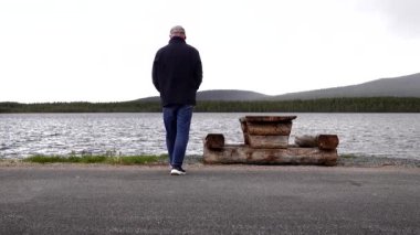 Arjeplog, İsveç Hornavan Gölü 'ndeki bir piknik masasında E95 otobanı boyunca dinlenme tesisinde bir adam..