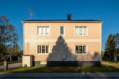 Sorsele, İsveç Sabahın erken saatlerinde bir ev cephesi ve ön cephedeki bir ağacın gölgesi.