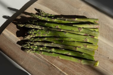 Mutfaktaki tahta kesme tahtasında taze kuşkonmaz.